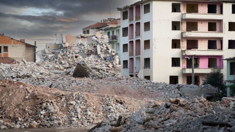 Earthquake damage in a city. Destroyed buildings after an earthquake. Collapsed buildings. Ruined city because of war. Airstrike damages a city. Urban transformation concept. Selective focus included