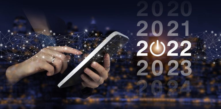 Loading year 2021 to 2022. Start concept. Hand touch white tablet with digital hologram 2022 sign on city dark blurred background. Welcome year 2022